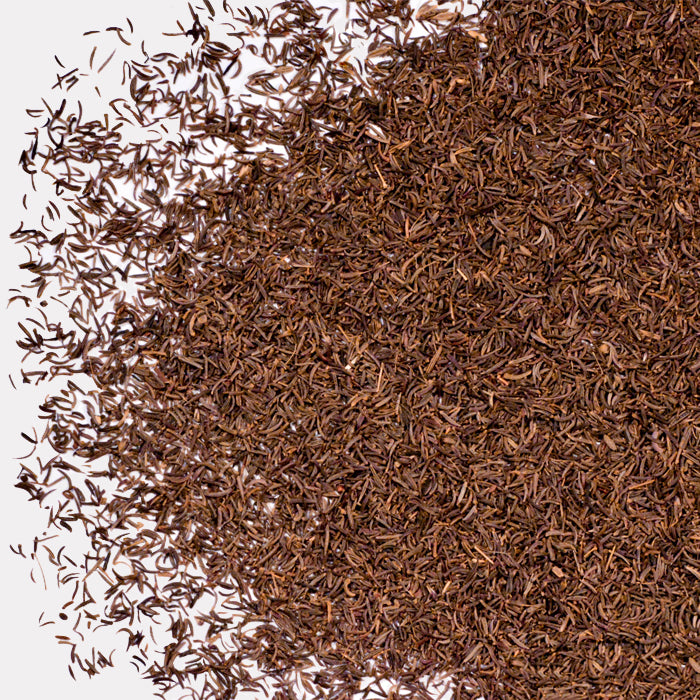 A close-up of a large pile of Black Cumin Seed by Whole Spice Inc., commonly used in Indian cuisine, scattered on a white background.