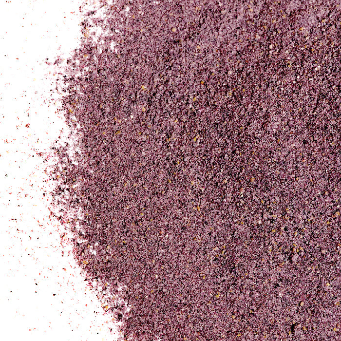 A close-up of Blueberry Fruit Powder by Whole Spice Inc. shows a pile of fine powder scattered on a white surface, with a granular, slightly uneven texture and thinner layers around the edges.