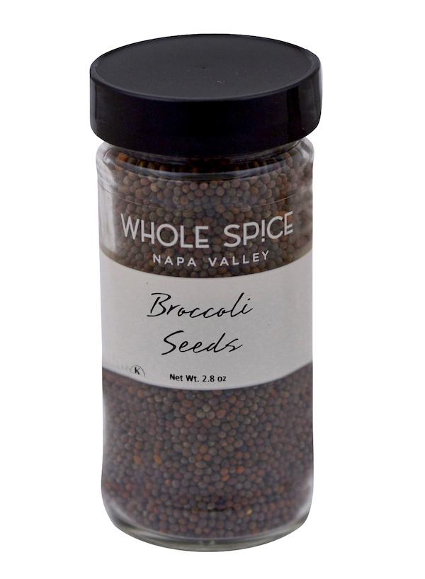 A glass jar with a black lid labeled Whole Spice Inc. Broccoli Seeds, Net Wt. 2.8 oz, filled with small, dark broccoli seeds—ideal for boosting nutrition in your favorite salads.