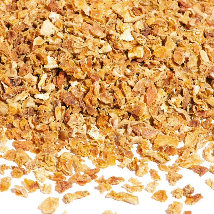 A close-up shows Whole Spice Inc.'s Butternut Squash Diced pieces, small, golden brown, and irregularly shaped, scattered on a white surface.