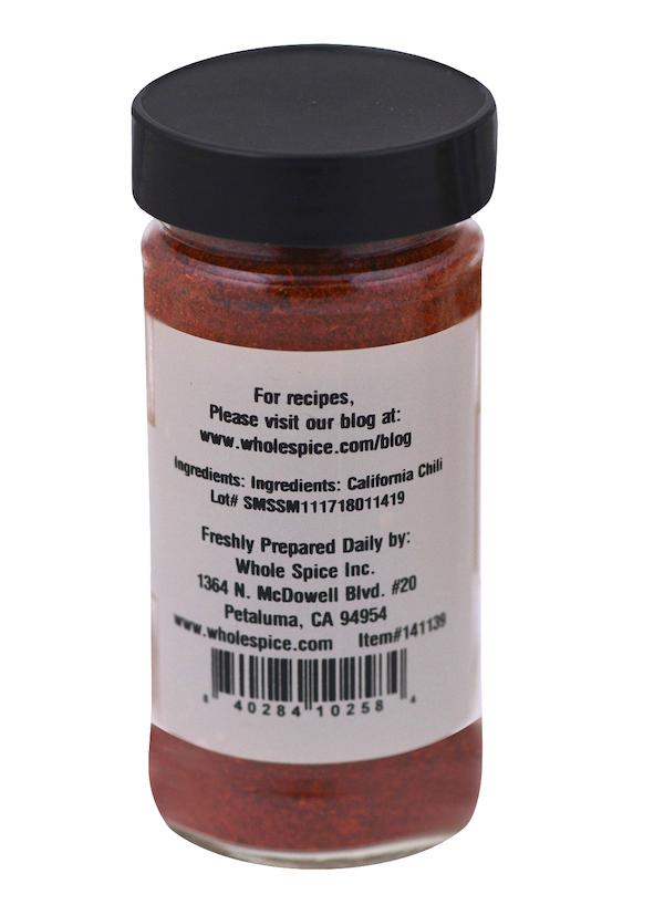 A clear spice jar with a black lid contains California Chili Powder from Whole Spice Inc., made from Anaheim peppers, with company details in Petaluma, CA and a website for recipes.