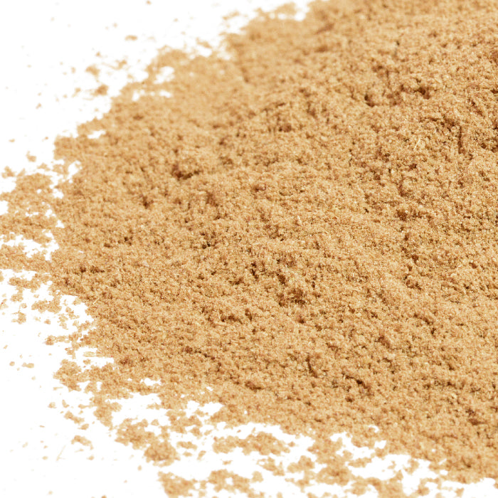 A close-up of fine, light brown Caraway Seed Ground Organic by Whole Spice Inc. spread across a white surface.