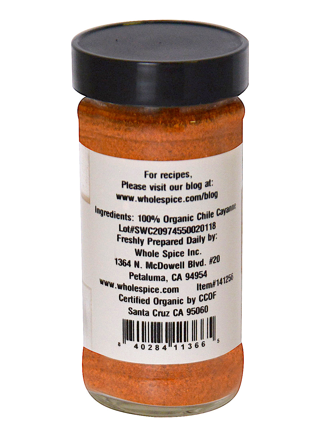 A glass jar of Whole Spice Inc. Cayenne Chili Powder Organic with a black lid. The label includes ingredients, preparation details, company info, website URL, barcode, and certification details for this bold chili spice.