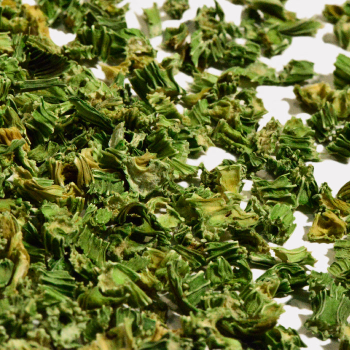 Close-up of scattered Celery Stalk Diced by Whole Spice Inc. on a white surface, showing crisp chopped pieces—ideal for adding fresh flavor to chicken noodle soup or mixing into vegetable juices.