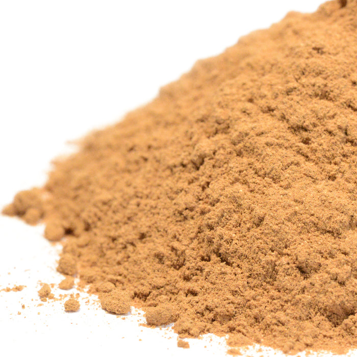 A close-up view of finely ground, light brown Cinnamon Powder Ceylon by Whole Spice Inc. on a white surface, reminiscent of baking spices from Sri Lanka.