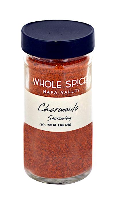 A glass jar with a black lid labeled Whole Spice Inc. Charmoula Seasoning contains a reddish-orange Moroccan-inspired spice blend. Net weight: 2.8 oz (79g).