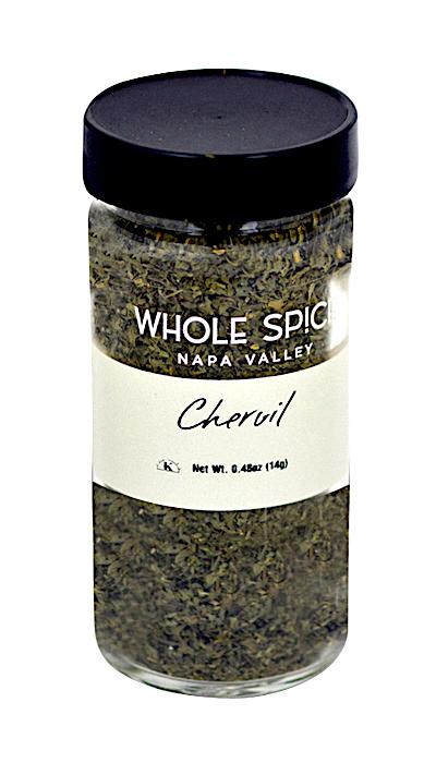 A glass jar with a black lid labeled “Whole Spice Inc. Chervil” holds dried chervil leaves, also called French parsley, valued for their subtle herbal-anise flavor. Net weight: 0.48 oz (14g).