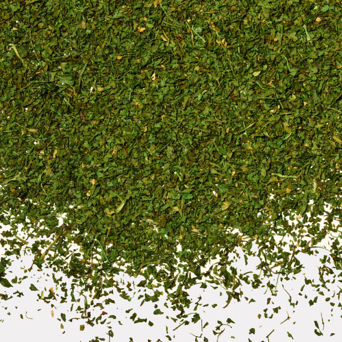 A close-up of dried, chopped Chervil by Whole Spice Inc.—also called French parsley—scattered on a white surface.