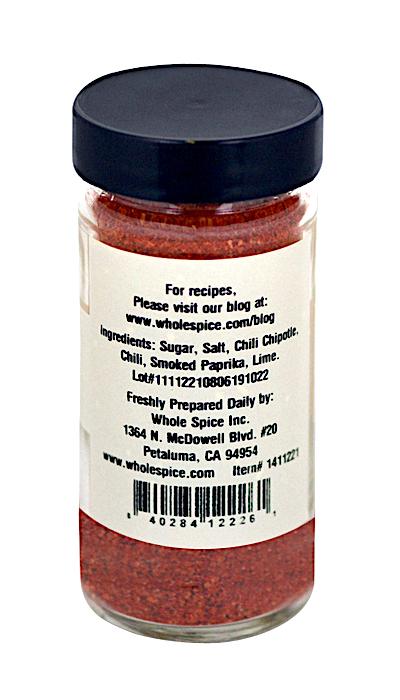 A clear spice jar with a black lid from Whole Spice Inc. contains Chili Lime Seasoning, featuring sugar, salt, chili chipotle, smoked paprika, and lime. The label shows the product name, manufacturer details, and barcode.
