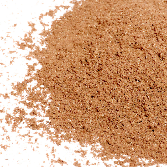 A close-up shows finely ground Chinese Five Spice-North China Style by Whole Spice Inc. spread on a white surface, highlighting how regional spice blends can vary in color and texture.