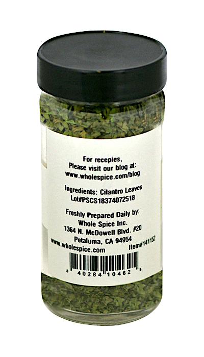 A clear spice jar with a black lid from Whole Spice Inc. contains Cilantro Leaves, ideal for spicy dishes. The back label lists cilantro leaves as the ingredient, provides manufacturer info, and features a recipe website.