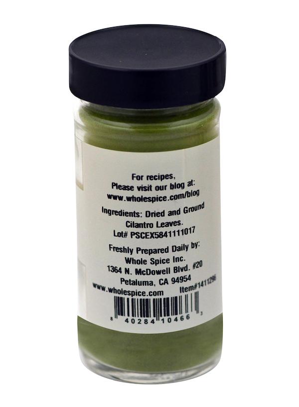 A clear spice jar with a black lid contains green Cilantro Powder by Whole Spice Inc. The label includes the name, manufacturer’s address, website, and barcode—cilantro is a popular culinary herb in Mexican cuisine.