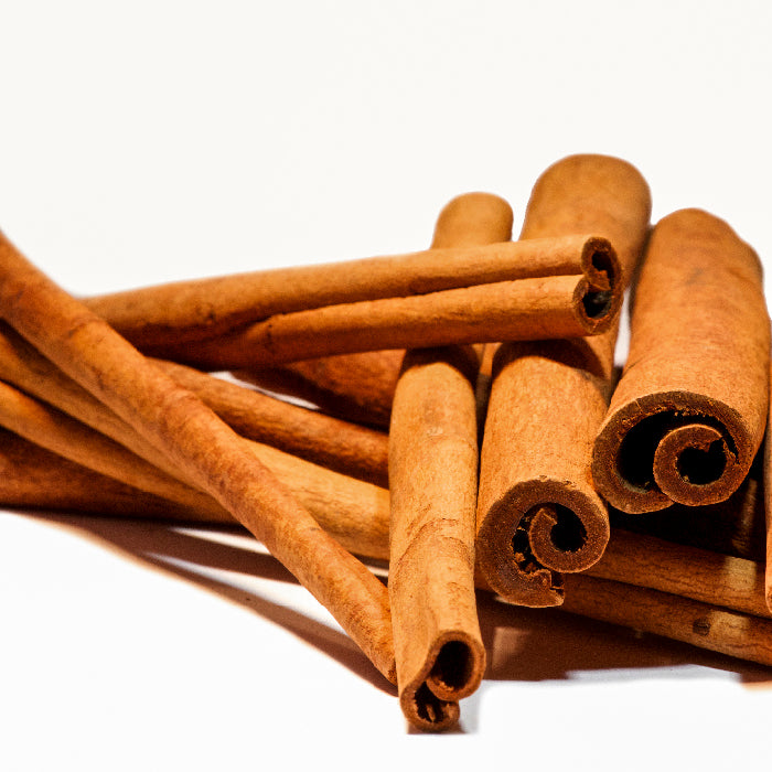 A close-up of Whole Spice Inc. Cinnamon Sticks 6 inch, stacked on a white background. These brown sticks from Cinnamomum burmanii show a characteristic curled and rolled appearance at the ends.