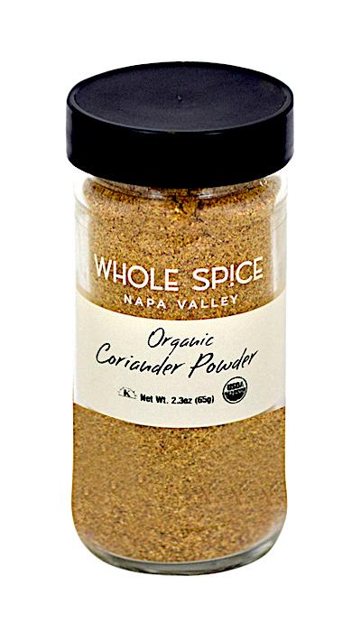 A glass jar with a black lid holds Whole Spice Inc. Coriander Powder Organic (2.3 oz/65g). The label shows the brand, product name, weight, and organic certification—ideal for Thai curries or pickling spices.