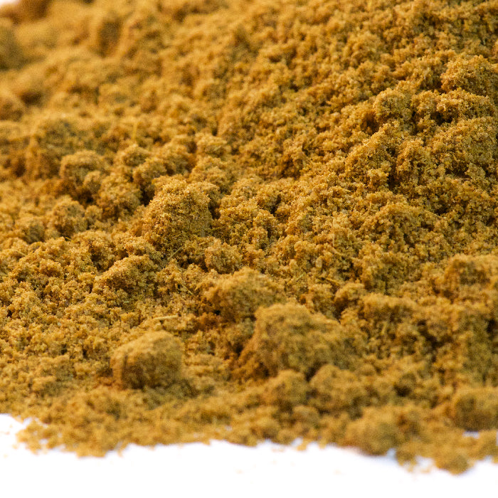 A close-up of finely ground brownish-yellow Cumin Powder Organic by Whole Spice Inc. is shown piled on a white surface.