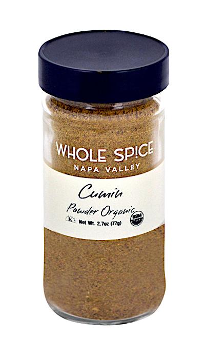A glass jar with a black lid holds Cumin Powder Organic by Whole Spice Inc., ideal for blending into spice mixes like Garam Masala. The label shows the brand name and product, plus a small USDA organic logo.