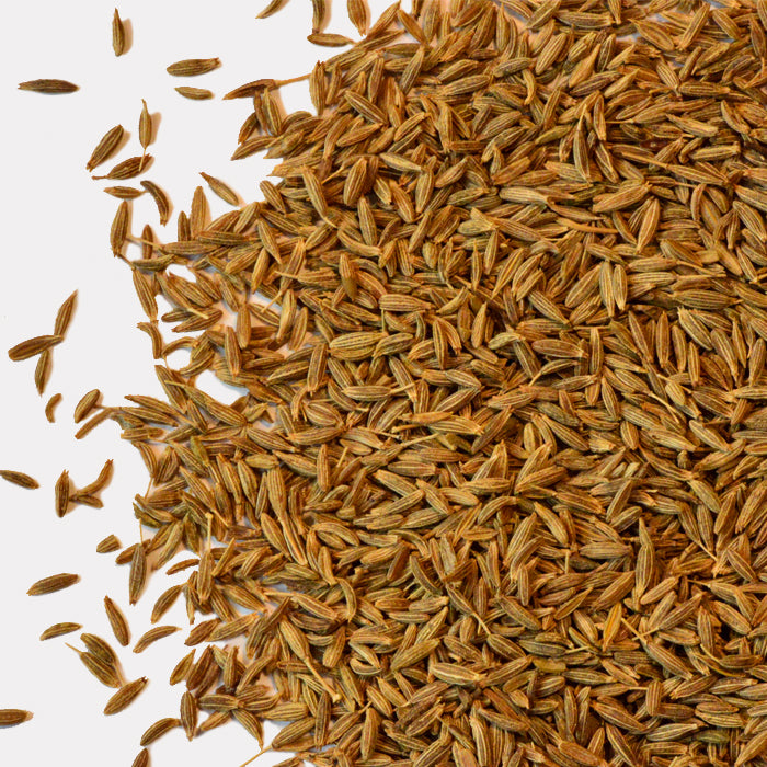 A close-up of Whole Spice Inc. Cumin Seeds shows their elongated, brown seeds with light stripes scattered on a white background—a classic spice essential for savory dishes.
