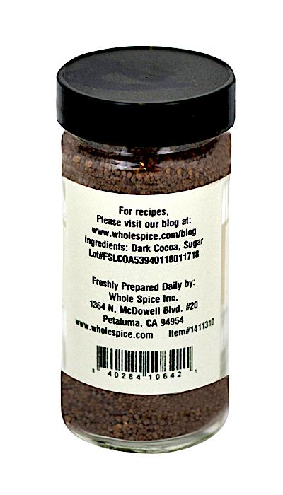 Whole Spice Inc. Dark Cocoa Sugar comes in a clear glass jar with a black lid, filled with rich cocoa sugar granules. The label features ingredients and directs chocolate lovers to gourmet sugar recipes on the Whole Spice website.