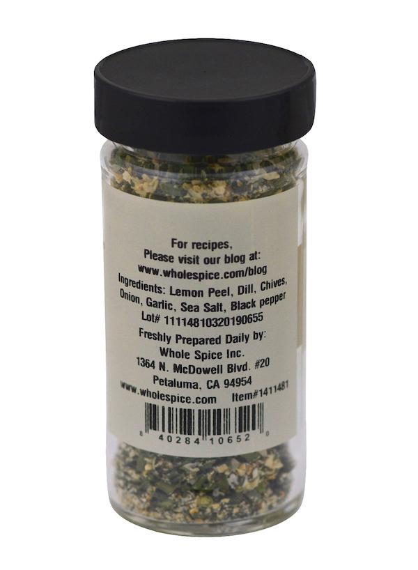 A clear spice jar with a black lid labeled "Dill Seasoning" from Whole Spice Inc. lists dill, lemon peel, chives, onion, garlic, sea salt, and black pepper—ideal as a dip base or veggie seasoning—with company info displayed.