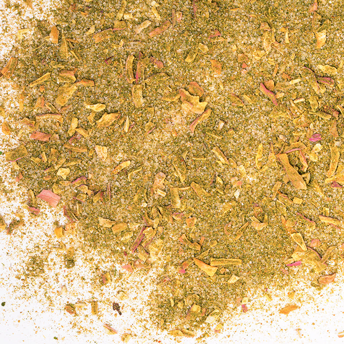 Close-up of Whole Spice Inc. Thai Seasoning, a coarse, flaky blend of dried herbs and spices in green, yellow, and brown tones on a white background—perfect for authentic Thai dishes.