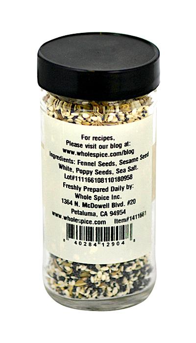 A clear spice jar with a black lid contains Everything sans Bagel by Whole Spice Inc.—a blend of fennel seeds, sesame seeds, poppy seeds, and sea salt. The label lists supplier and contact info for convenience.