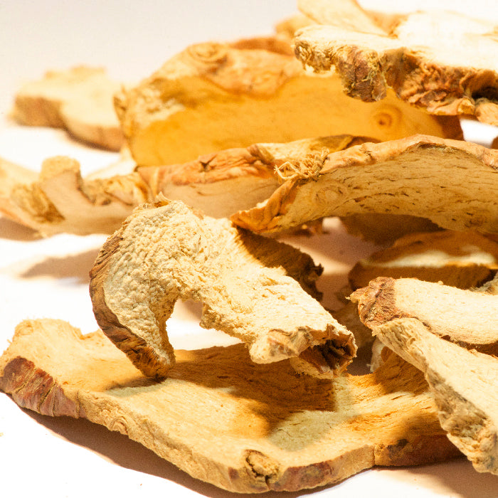 Close-up of dried, sliced Galangal Root by Whole Spice Inc., showing its rough texture and light brown color—an essential ingredient in many traditional recipes.