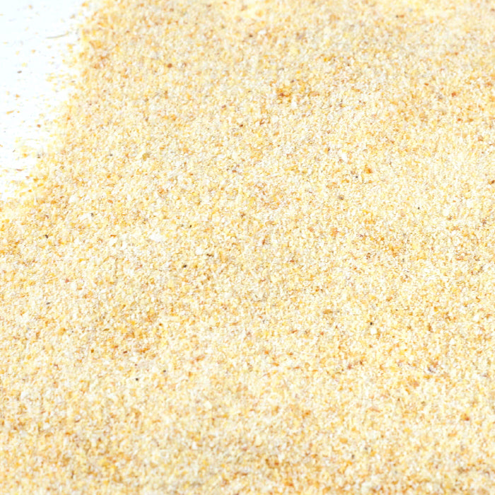 A close-up of fine, pale yellow powder spread on a white surface, perfectly capturing the appearance of Whole Spice Inc. Garlic Granulated Organic.