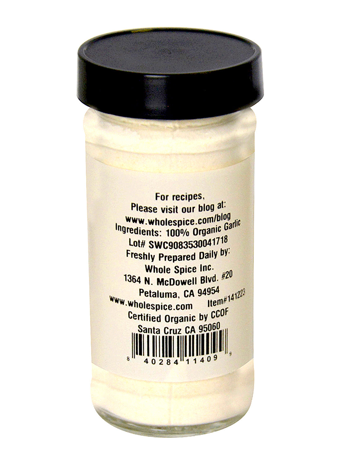 A glass jar with a black lid contains Garlic Powder Organic by Whole Spice Inc. The label lists dehydrated garlic as the ingredient, plus manufacturer’s address, website, lot number, certifications, and a blog link for recipes.