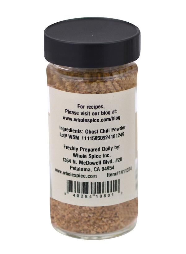 A glass jar with a black lid contains Ghost Salt by Whole Spice Inc., a fiery spicy seasoning. The label shows the ingredient, company info, barcode, and a website offering recipes.