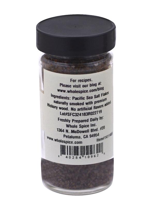 A labeled jar of Whole Spice Inc. Hickory Smoked Sea Salt Coarse offers rich, wood-grilled aromas for flavorful seasoning.