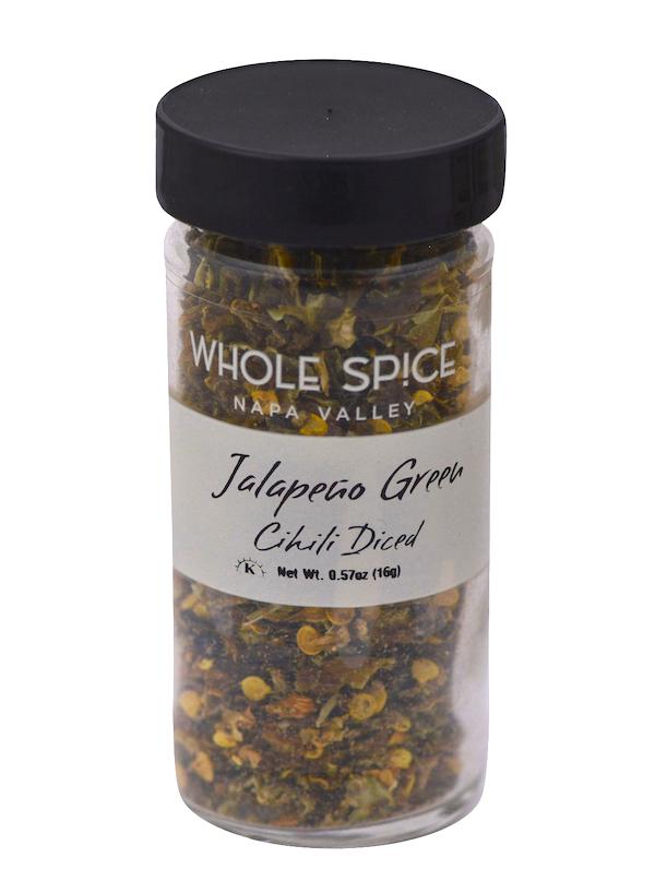 A clear plastic jar with a black lid holds Whole Spice Inc. Jalapeño Green Chili Diced, Net Wt. 0.57oz (16g)—ideal for adding dried chili pepper heat to your dishes.