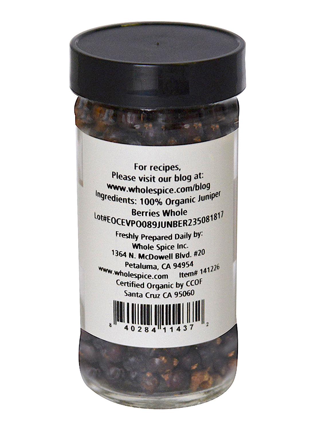 A clear jar with a black lid from Whole Spice Inc. contains Juniper Berries Organic, cherished in Scandinavian dishes for their pine flavor. The back label shows ingredients, company info, certification, barcode, and a recipe website.