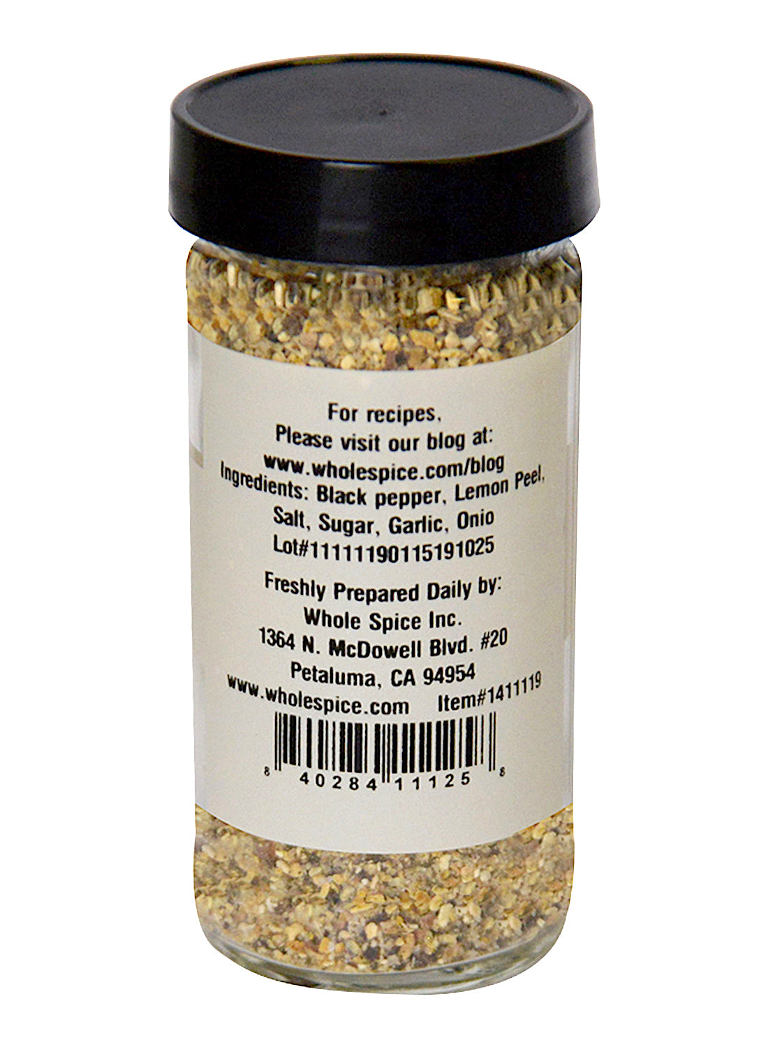 A clear spice jar with a black lid displays a Lemon Pepper Salt label by Whole Spice Inc., listing black pepper, lemon peel, salt, sugar, and garlic as ingredients. Company contact details are above the barcode. Great for meat and poultry.
