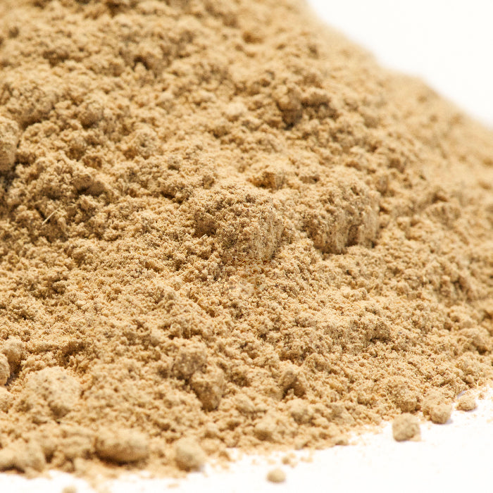 A close-up of a pile of finely ground, light brown Licorice Stick Powder by Whole Spice Inc. on a white surface.
