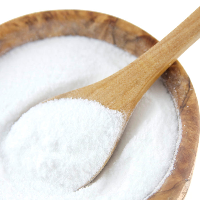 A wooden spoon scoops Malt Vinegar Sea Salt by Whole Spice Inc. from a wooden bowl, perfect for seasoning crispy French fries or fish and chips, set against a white background.