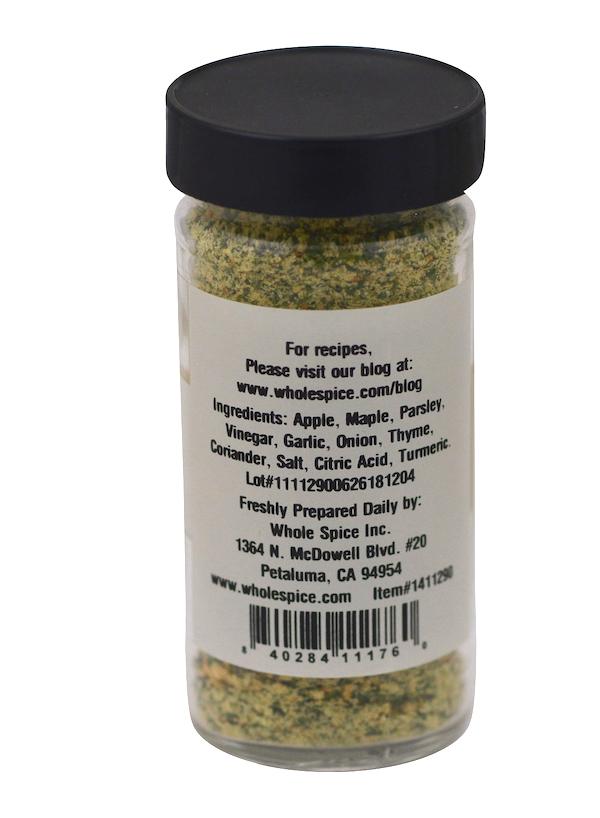 A clear plastic jar of Maple Apple Sausage Rub by Whole Spice Inc. is shown, with a black lid, visible spices, and a label listing ingredients, contact info, address, website, and a barcode. Ideal as a savory meat seasoning.