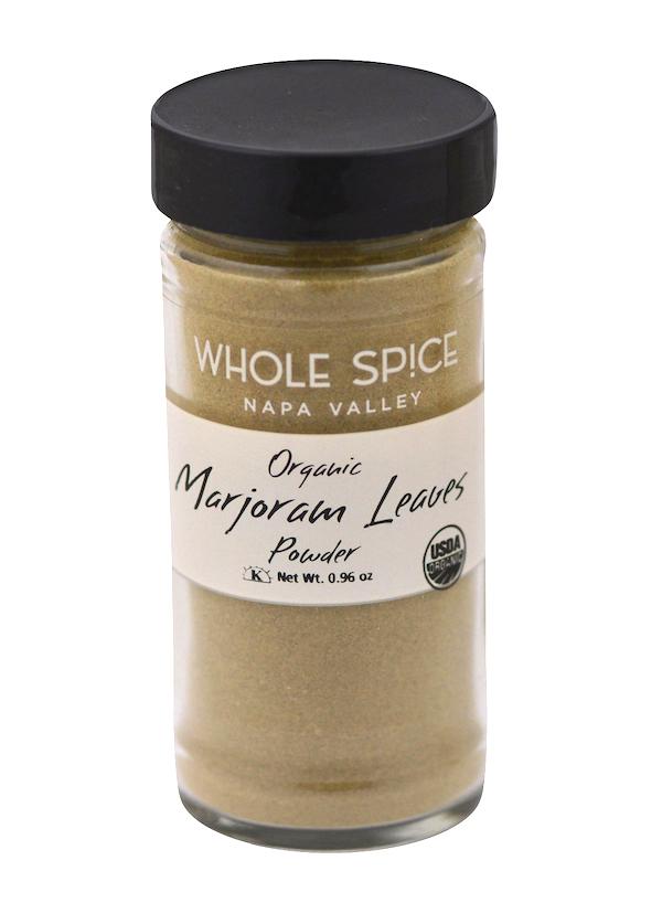 A glass jar with a black lid, labeled Whole Spice Inc. Marjoram Powder Organic, holds light greenish-brown organic herbs. The jar features USDA Organic certification and highlights premium marjoram leaves.