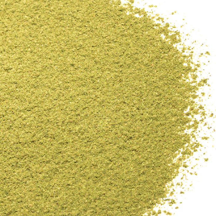 A close-up of Whole Spice Inc. Marjoram Powder, a fine, light green spice, spread across a white background.