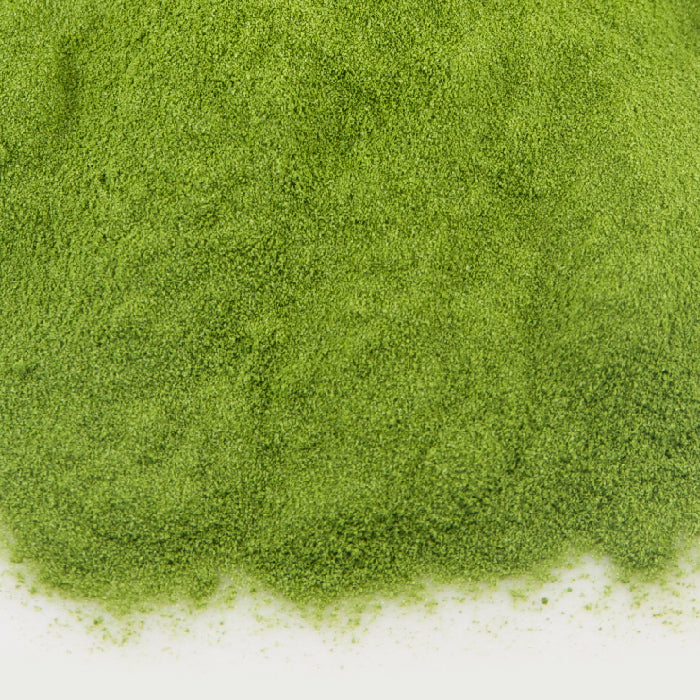 A close-up of vibrant green Whole Spice Inc. Ceremonial Matcha (100g bag) spread on a white surface, ideal for crafting a refreshing matcha milkshake.