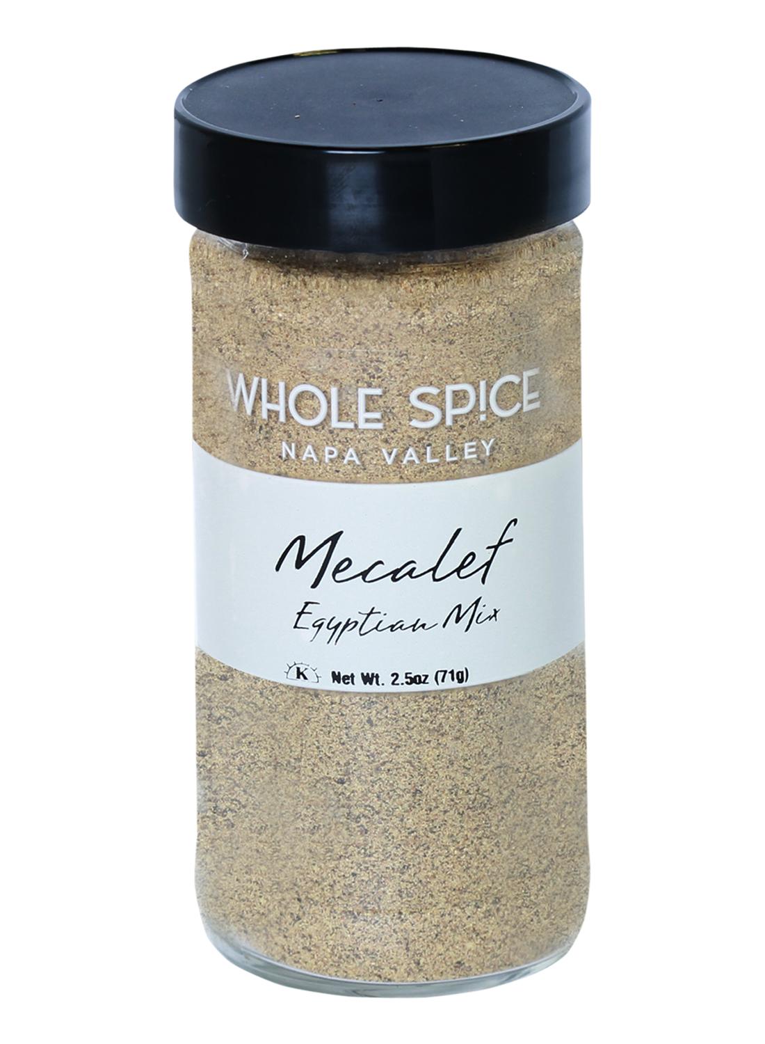 Whole Spice Inc. Mecalef Egyptian Mix is a 2.5 oz (71g) finely ground beige spice blend in a clear jar with black lid, ideal for adding authentic Egyptian flavor to chicken or vegetable dishes.