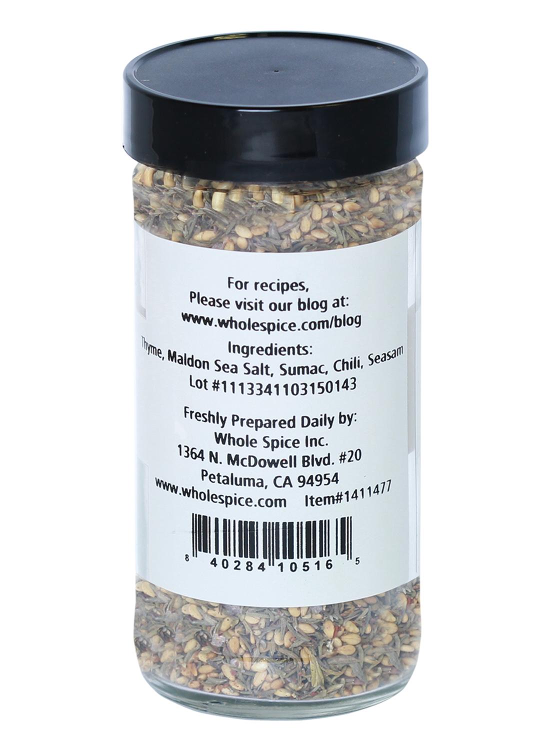A clear jar with a black lid contains Mediterranean Breakfast Seasoning by Whole Spice Inc. The label lists thyme, Maldon sea salt, sumac spice, chili, sesame seeds, plus supplier contact info and a barcode.