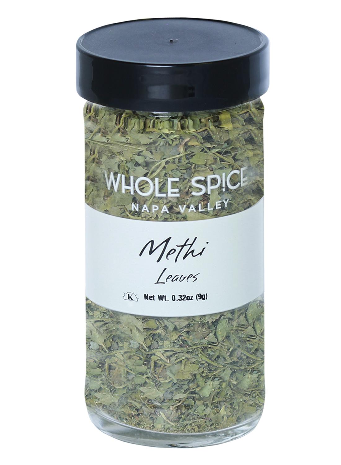 A clear glass jar with a black lid containing dried Methi Leaves by Whole Spice Inc.; label states Net Wt. 0.32oz (9g), commonly used in Indian cooking.