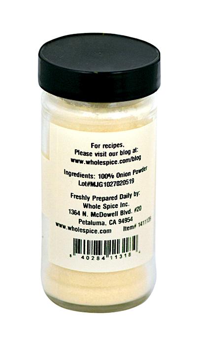 A clear spice jar with a black lid, labeled "Onion Powder" by Whole Spice Inc., contains 100% onion powder. The label lists ingredients, lot number, manufacturer details, and website, making it an essential cooking ingredient.
