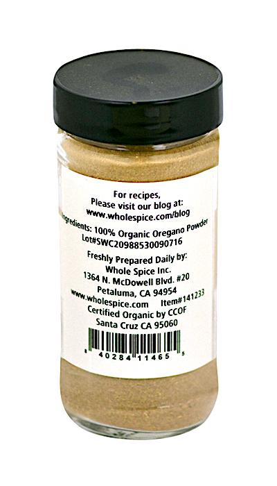 A clear spice jar with a black lid contains Whole Spice Inc. Oregano Powder Organic—a 100% organic Mediterranean herb. The label lists ingredients, origin, barcode, website, and quality certification for assurance.