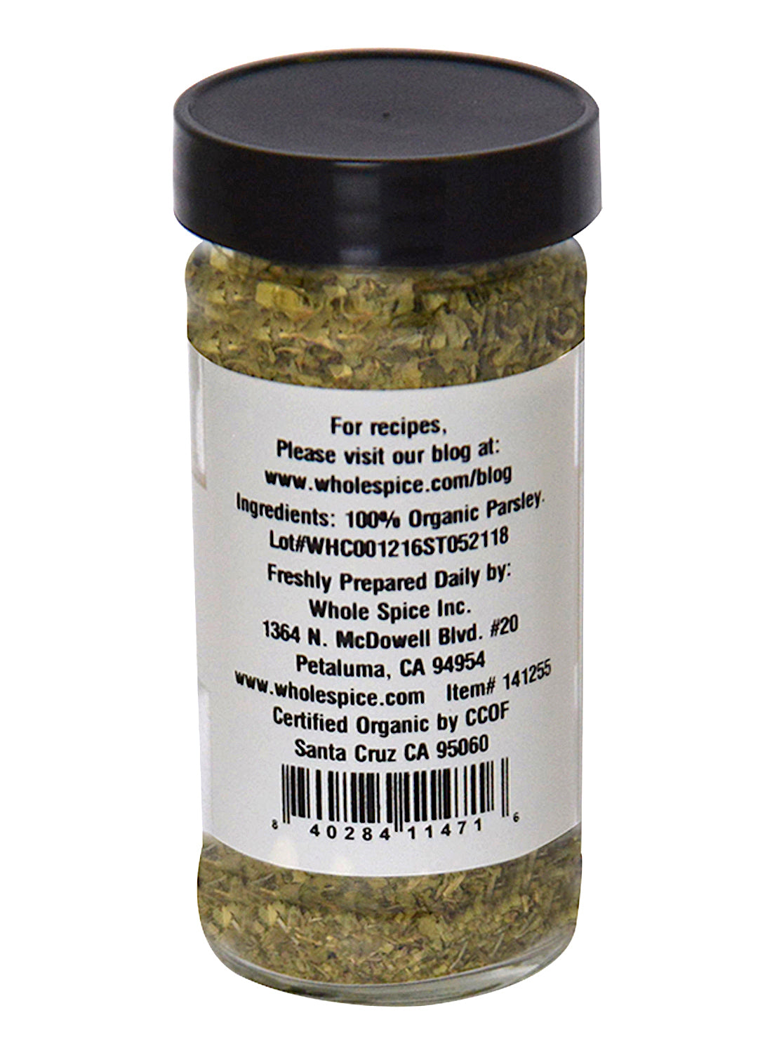 A clear spice jar with a black lid holds chopped Parsley Flakes Organic by Whole Spice Inc. The label lists 100% organic parsley, company info, a barcode, and website details for this essential culinary herb.