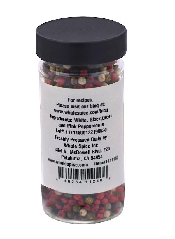 A clear jar of Peppercorns Mixed by Whole Spice Inc. displays a colorful blend of white, black, green, and pink peppercorns. The label lists ingredients, preparation instructions, company info, and a barcode.