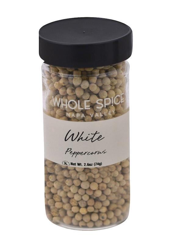 A clear spice jar with a black lid, filled with Peppercorns White. The label reads “Whole Spice Inc., Peppercorns White, Net Wt. 2.6oz (74g).” Ideal for white sauces and cooking that needs mild pepper flavor.