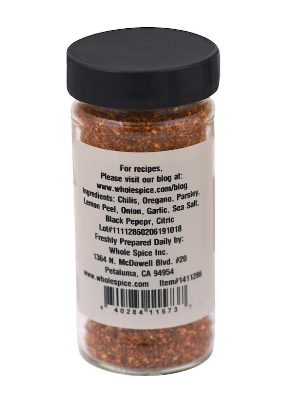 The Peri Peri Blend from Whole Spice Inc. comes in a clear jar with a black lid, featuring a label listing chilis, oregano, parsley, and onion—ideal for spicy marinades or as Peri Peri seasoning. Contact info and recipe site also provided.