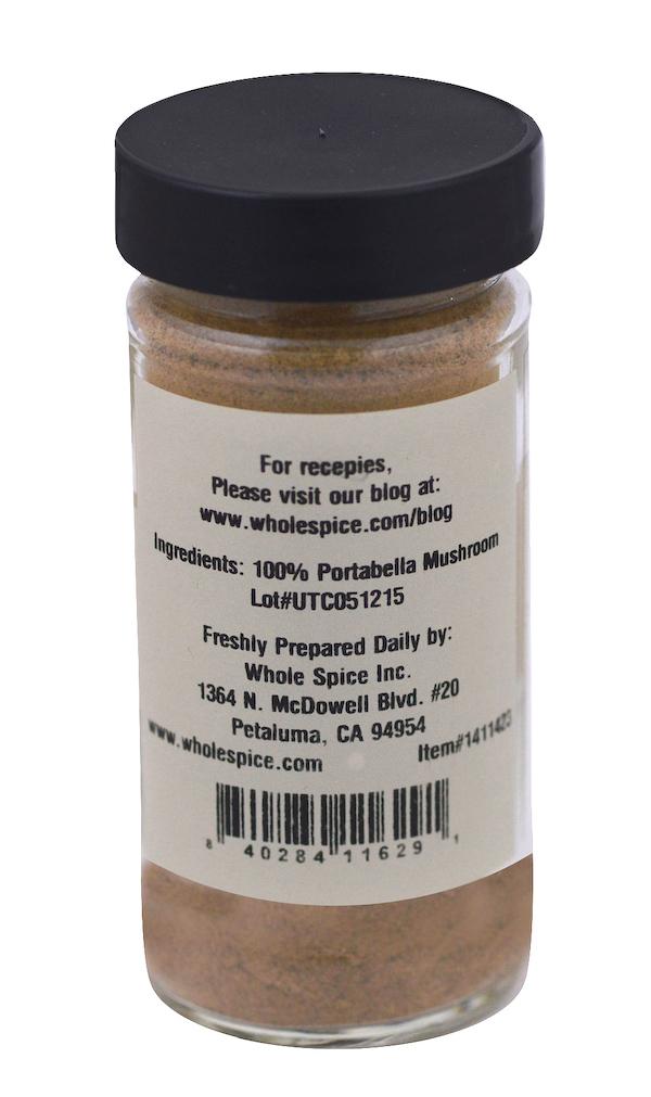 A clear glass jar with a black lid contains Whole Spice Inc. Portobello Mushroom Powder. The label lists 100% portobello mushroom as the ingredient and provides company contact info plus a website for Mushroom Pasta recipes.