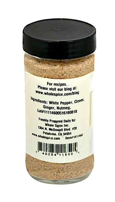 A clear spice jar from Whole Spice Inc. with a black lid and label lists white pepper, cloves, ginger, and nutmeg as ingredients in Quatre Epices (Four Spices), a classic French blend. Contains light brown powder; website and barcode shown.